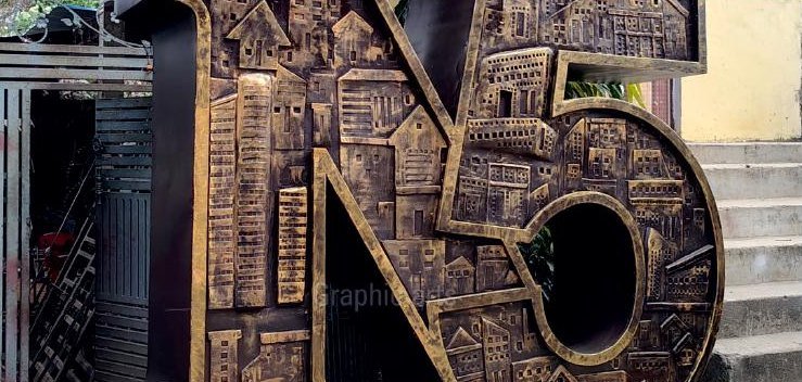 The same N50 installation in daylight, showing the bronze-finished cut-metal cityscape of towers and buildings that forms the numerals